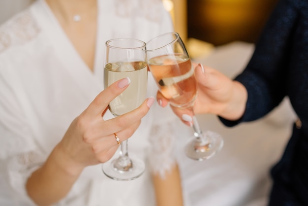 Linda noiva e dama de honra brindando com champanhe e se divertindo na manhã do casamento. Alegres namoradas jovens levantar um brinde e tilintar de copos. Dia da noiva. Dia do casamento