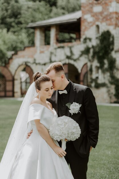 Linda noiva e noivo abraçando e beijando no dia do casamento ao ar livre