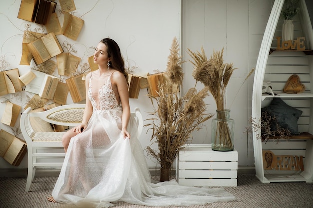 linda noiva em um vestido branco em um fundo preto perto do cenário seco de flores