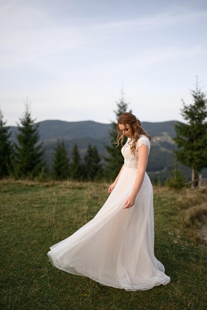 Linda noiva em um vestido de noiva branco em um fundo de montanhas