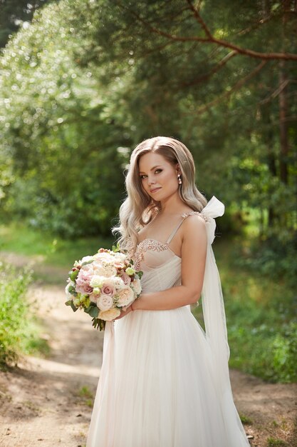 Linda noiva em um vestido de noiva luxuoso com um buquê de noiva com flores de peônia e rosas