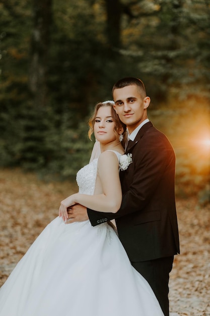 Linda noiva em um vestido longo branco. Noivo bonito em um terno preto. Casal em um parque de verão