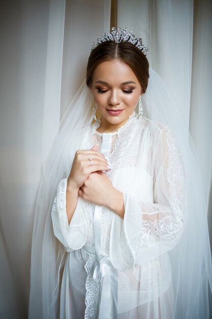 Linda noiva em uma manhã de casamento em um roupão de banho e véu