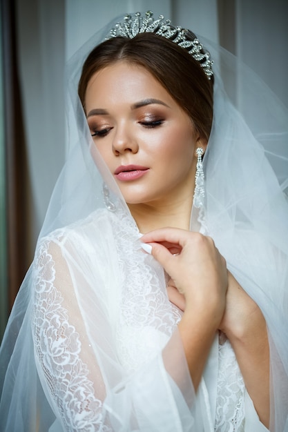 Linda noiva em uma manhã de casamento em um roupão de banho e véu