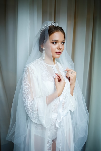 Linda noiva em uma manhã de casamento em um roupão de banho e véu