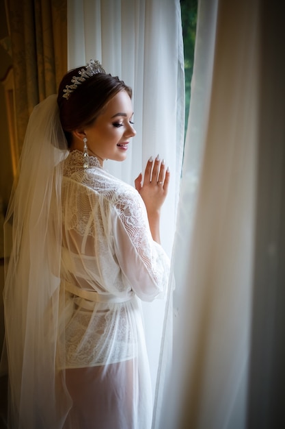 Linda noiva em uma manhã de casamento em um roupão de banho e véu