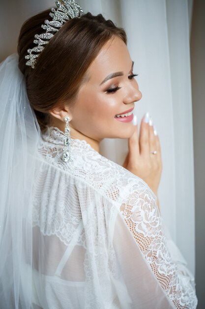 Linda noiva em uma manhã de casamento em um roupão de banho e véu