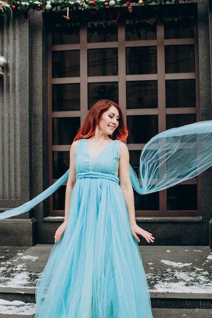 linda noiva ruiva em um vestido longo azul no fundo da cidade