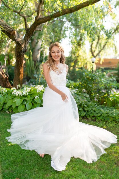 Foto linda noiva sorridente em um vestido de noiva branco no jardim