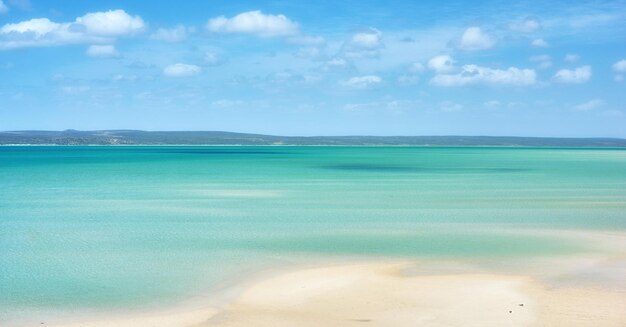 Linda paisagem de praia e horizonte sob céu azul nublado copia o espaço com cenário oceânico calmo e tranquilo Um mar com uma montanha ao fundo Um feriado costeiro tranquilo ou férias à beira-mar