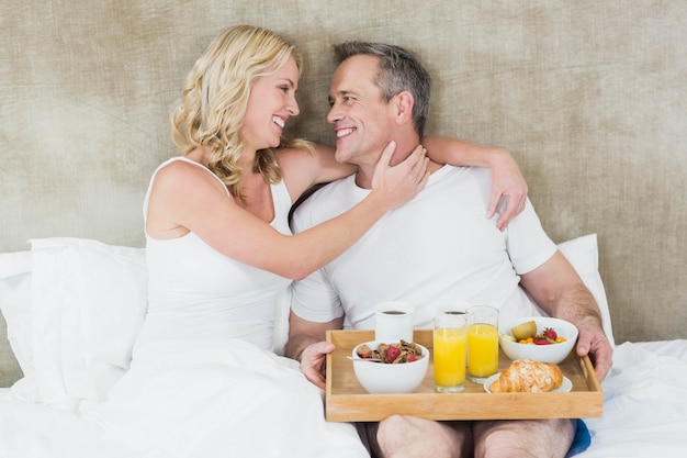 Linda pareja desayunando en la cama en su habitación.