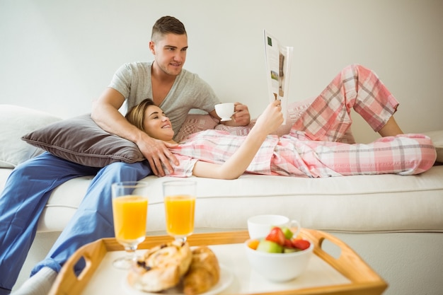 Linda pareja descansando en el sofá en el desayuno