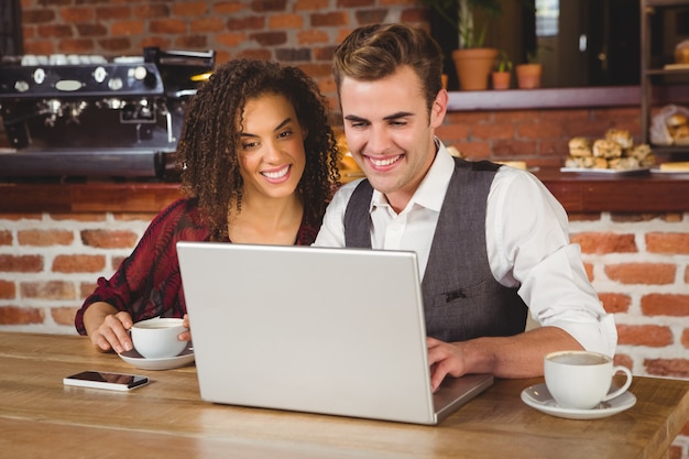 Linda pareja en una fecha viendo fotos en una computadora portátil