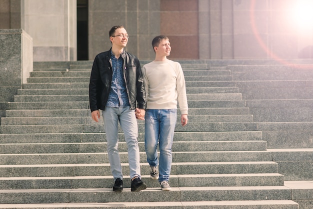 Linda pareja gay en la ciudad, tiernos besos suaves, sonriendo