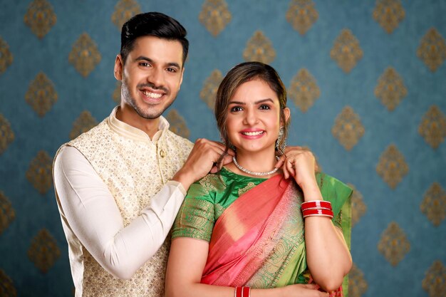 Una linda pareja india atando un collar a su esposa mientras posan frente a la cámara