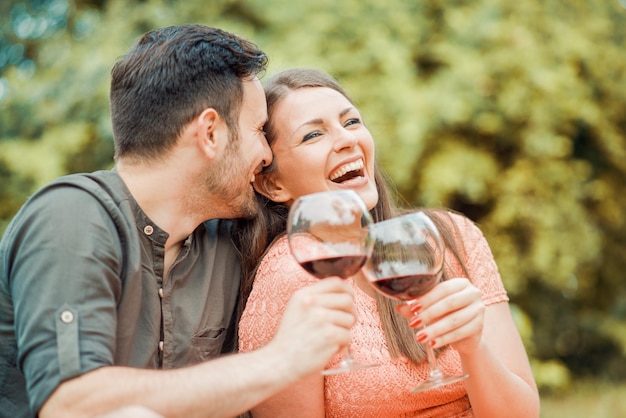 Linda pareja joven bebiendo vino en un picnic