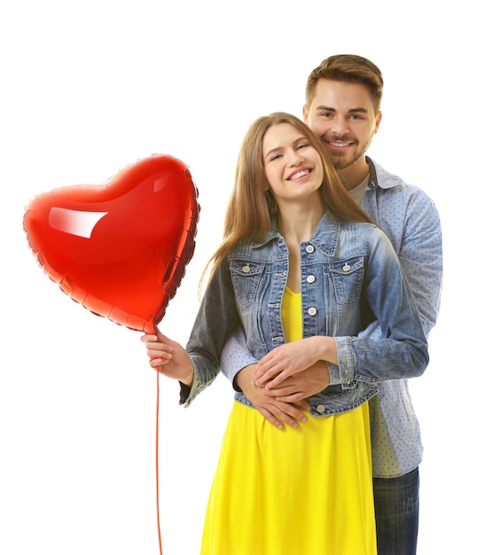 Linda pareja joven con globo en forma de corazón sobre fondo blanco.