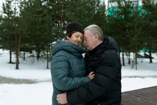 Una linda pareja jubilada caminando por el parque y abrazándose en el parque de invierno.