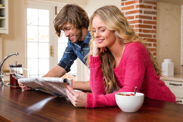 Linda pareja leyendo el periódico en la cocina