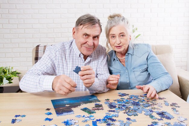 Foto una linda pareja de mayores resolviendo rompecabezas juntos en casa.