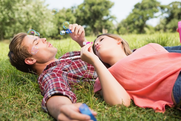 Linda pareja en el parque soplando burbujas