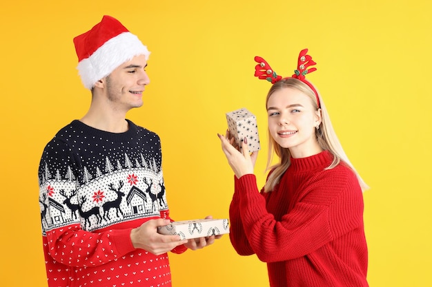 Linda pareja en ropa de Navidad sobre fondo amarillo