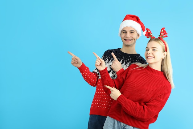 Linda pareja en ropa de Navidad sobre fondo azul.