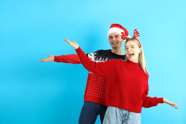 Linda pareja en ropa de Navidad sobre fondo azul.