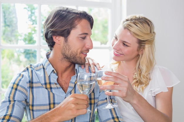 Linda pareja sonriente disfrutando de vino blanco juntos