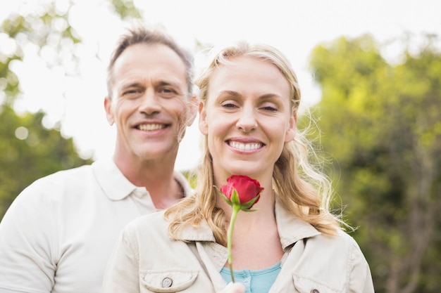 Linda pareja sosteniendo una rosa afuera