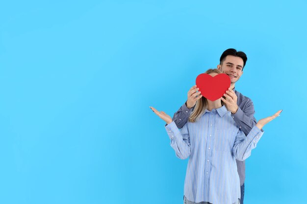 Linda pareja tiene corazón sobre fondo azul.