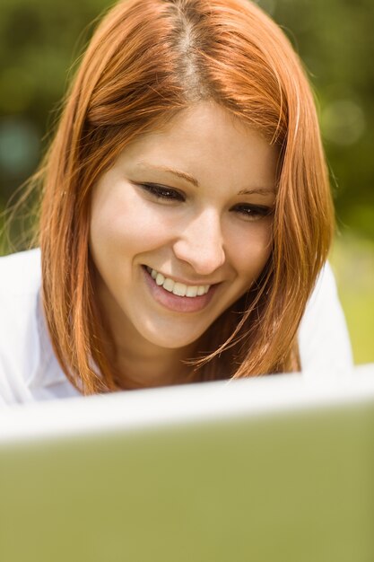 Linda pelirroja sonriendo con su computadora portátil