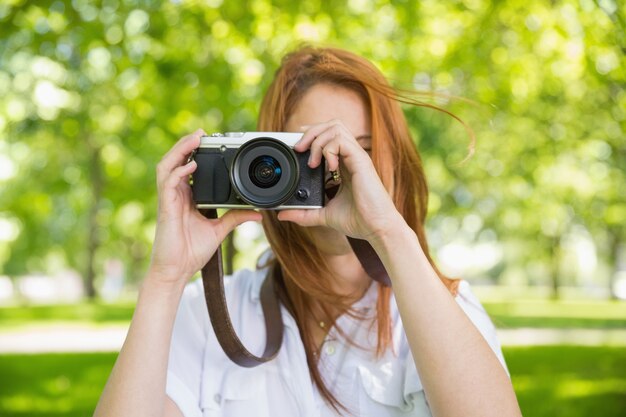 Linda pelirroja tomando una foto en el parque