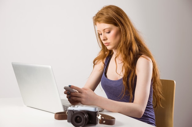 Linda pelirroja trabajando en la computadora portátil y la cámara