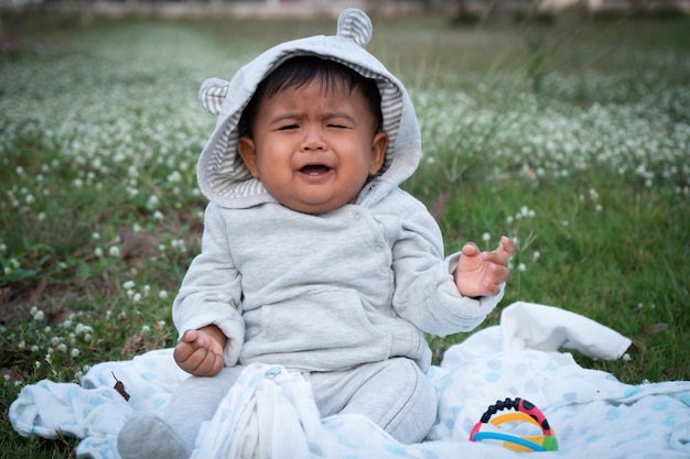 Linda pequeña asina bebé sentado en el jardín de flores blancas