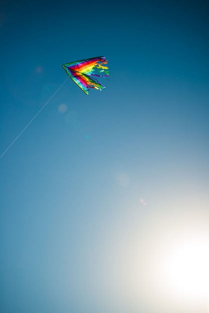 Foto linda pipa em cores brilhantes do arco-íris voa contra um céu azul ensolarado. infância do conceito de liberdade e ingenuidade. espaço de publicidade