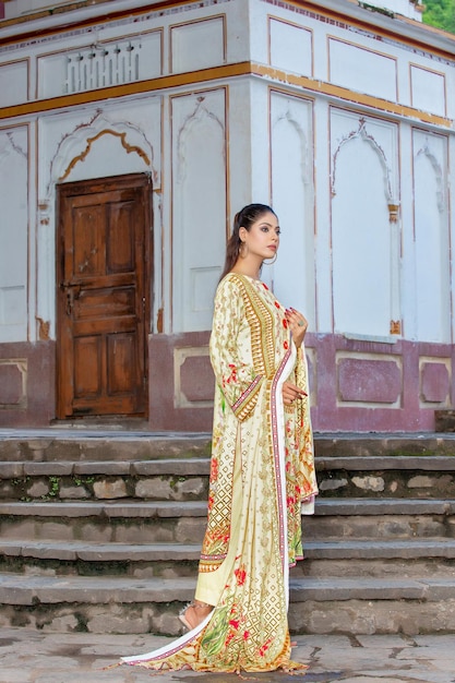 Linda pose de lado de menina nas escadas usando vestido de grife tradicional para sessão de fotos