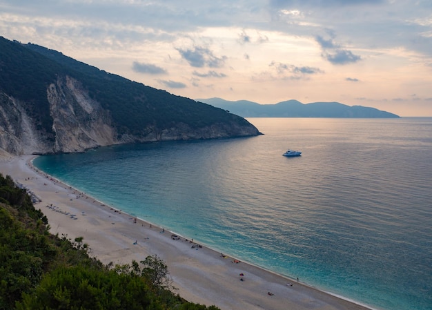 Linda praia de Myrtos com água turquesa no pôr do sol em Cefalônia no mar Jônico na Grécia