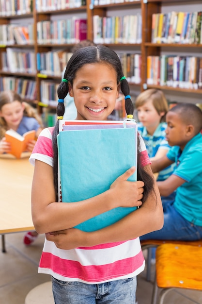 Foto linda pupila sonriendo a la cámara en la biblioteca