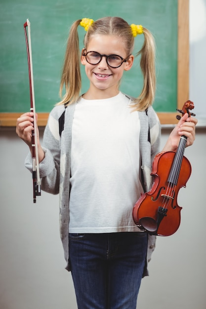 Linda pupila con violín en un aula