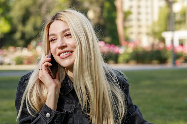 Una linda rubia hablando por teléfono en el parque