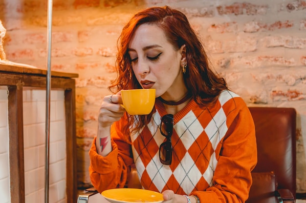 linda ruiva argentina caucasiana sentada em um restaurante tomando café