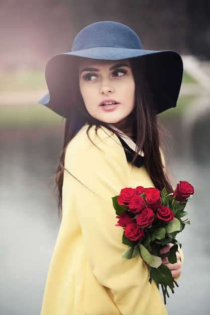 Linda senhora com flores de rosas vermelhas ao ar livre