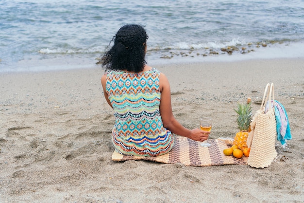 Linda senhora com uma taça de vinho na praia