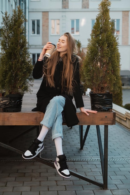 Linda senhora de cabelo comprido com café para viagem na rua Aluna para passear