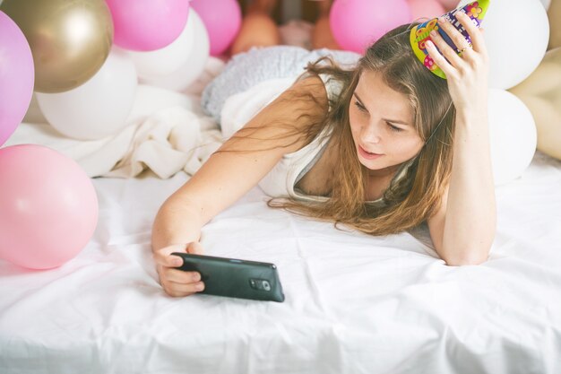 Linda senhora de pijama fazendo selfie no quarto dela usando o telefone