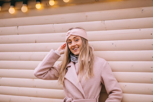 Foto linda senhora feliz e sorridente em elegante inverno leve bandagem cachecol casaco rosa posando na rua
