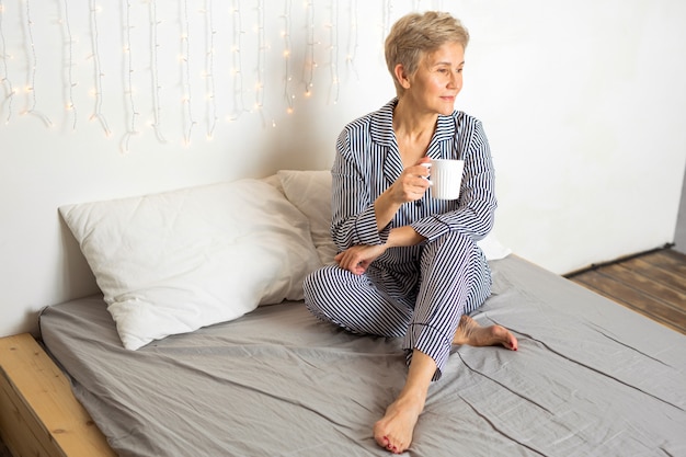 Linda senhora idosa de pijama na cama