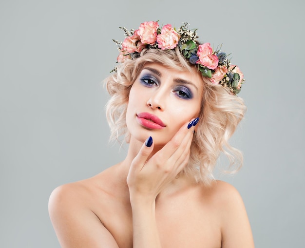 Linda senhora loira com flores no cabelo tocando sua mão seu rosto