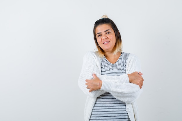 Linda senhora segurando os braços cruzados em uma camiseta, casaco de lã e parecendo alegre. vista frontal.